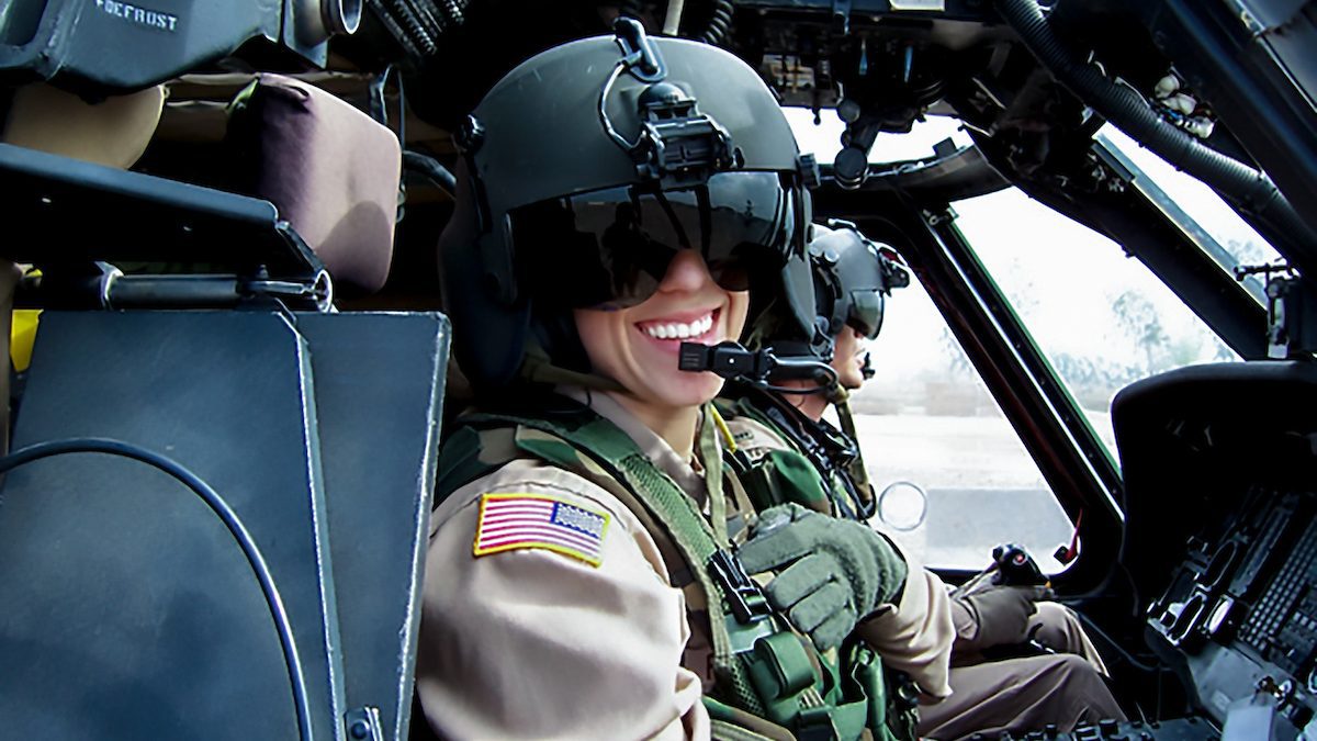 MBA@UNC alumna Allison Hughes in a flight suit and helmet at the controls of a military helicopter.