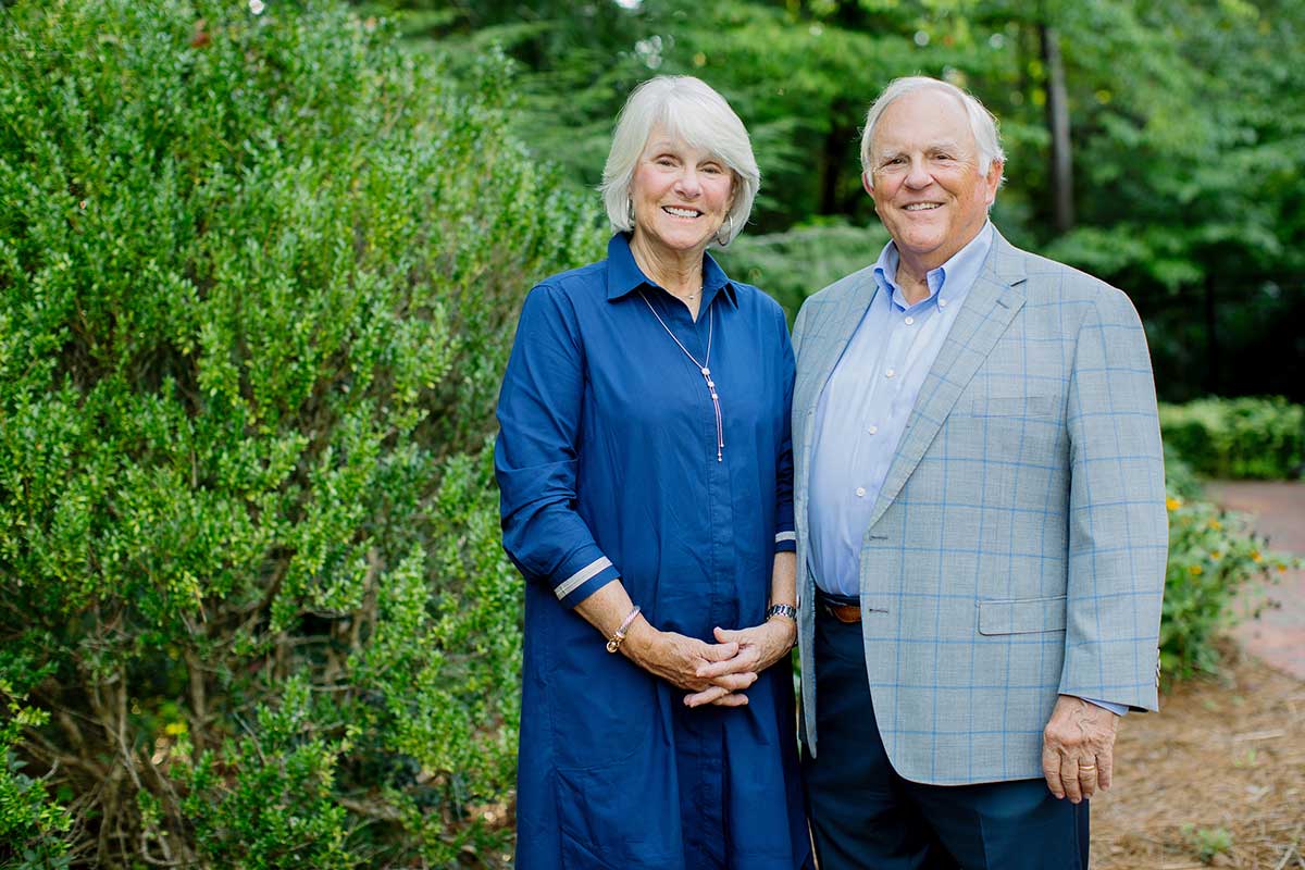 Jackie and Steve Bell pose outside in front of shrubbery.