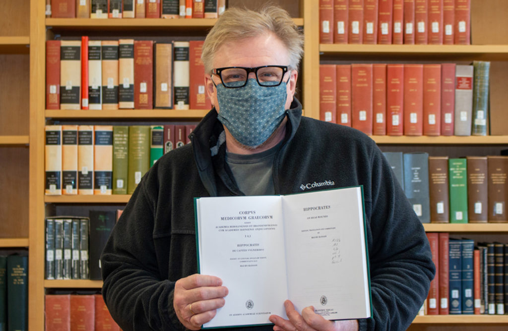 Professor Donald Haggis holds up a rare book.