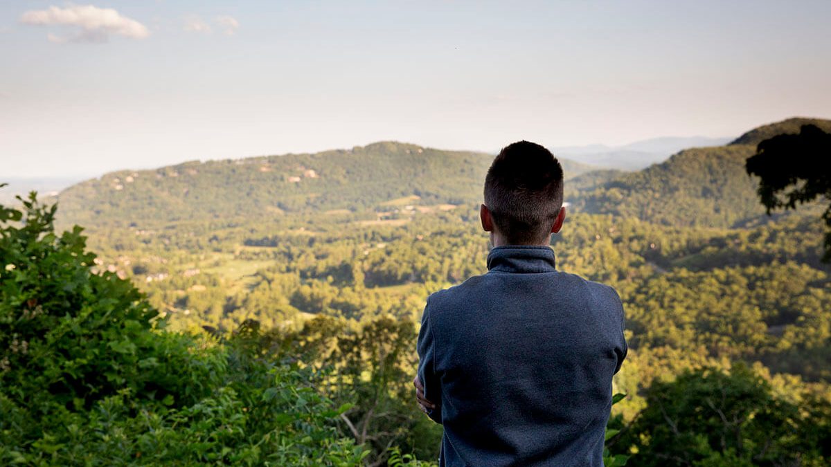 UNC medical student Travis Williams standing in front of a view of mountains, with his back to the camera