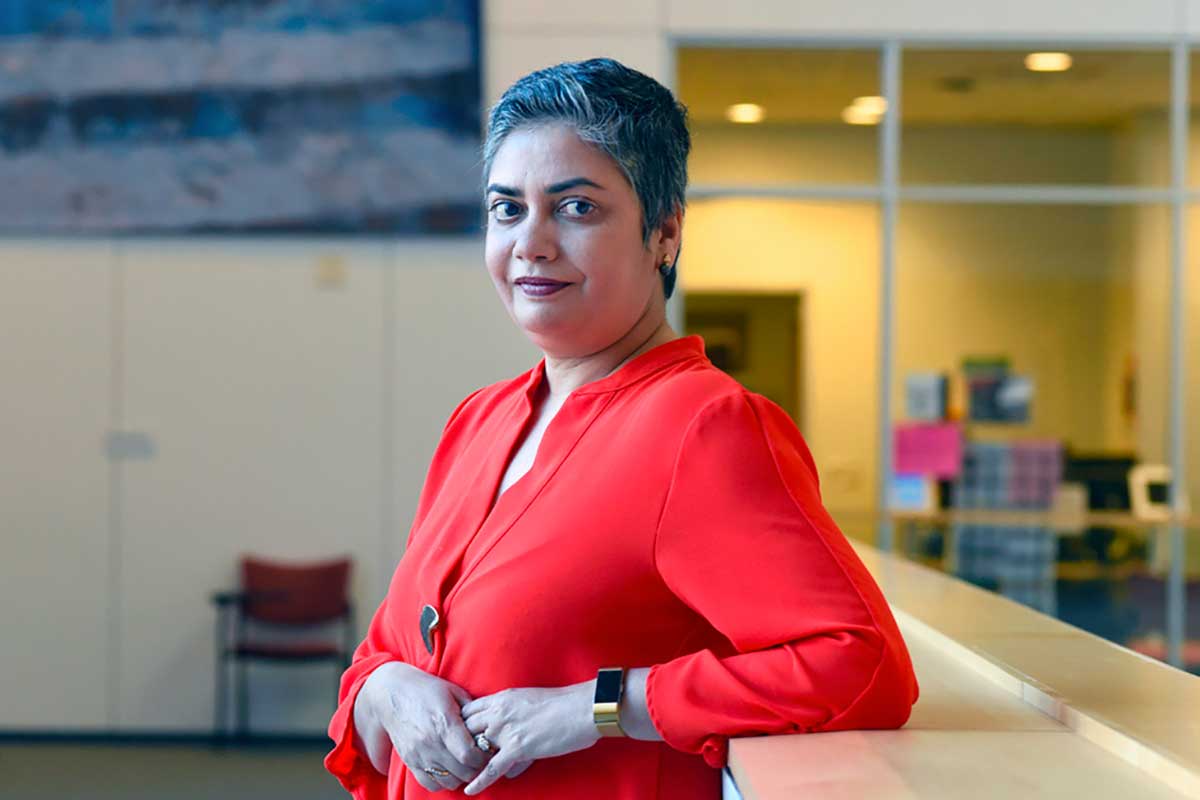 UNC-Chapel Hill Professor Anusha Chari poses against a railing in the Fedex Global Education Center.