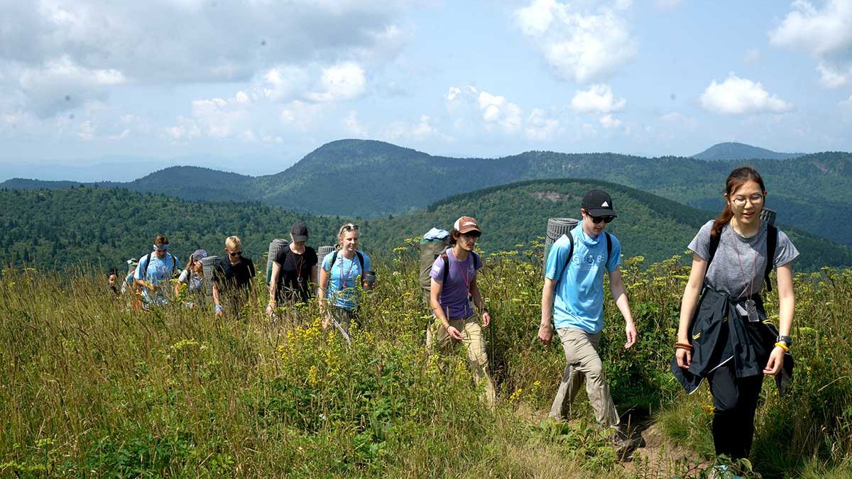 A line of university students hike across a ridge in the Blue Ridge Mountains of North Carolina.