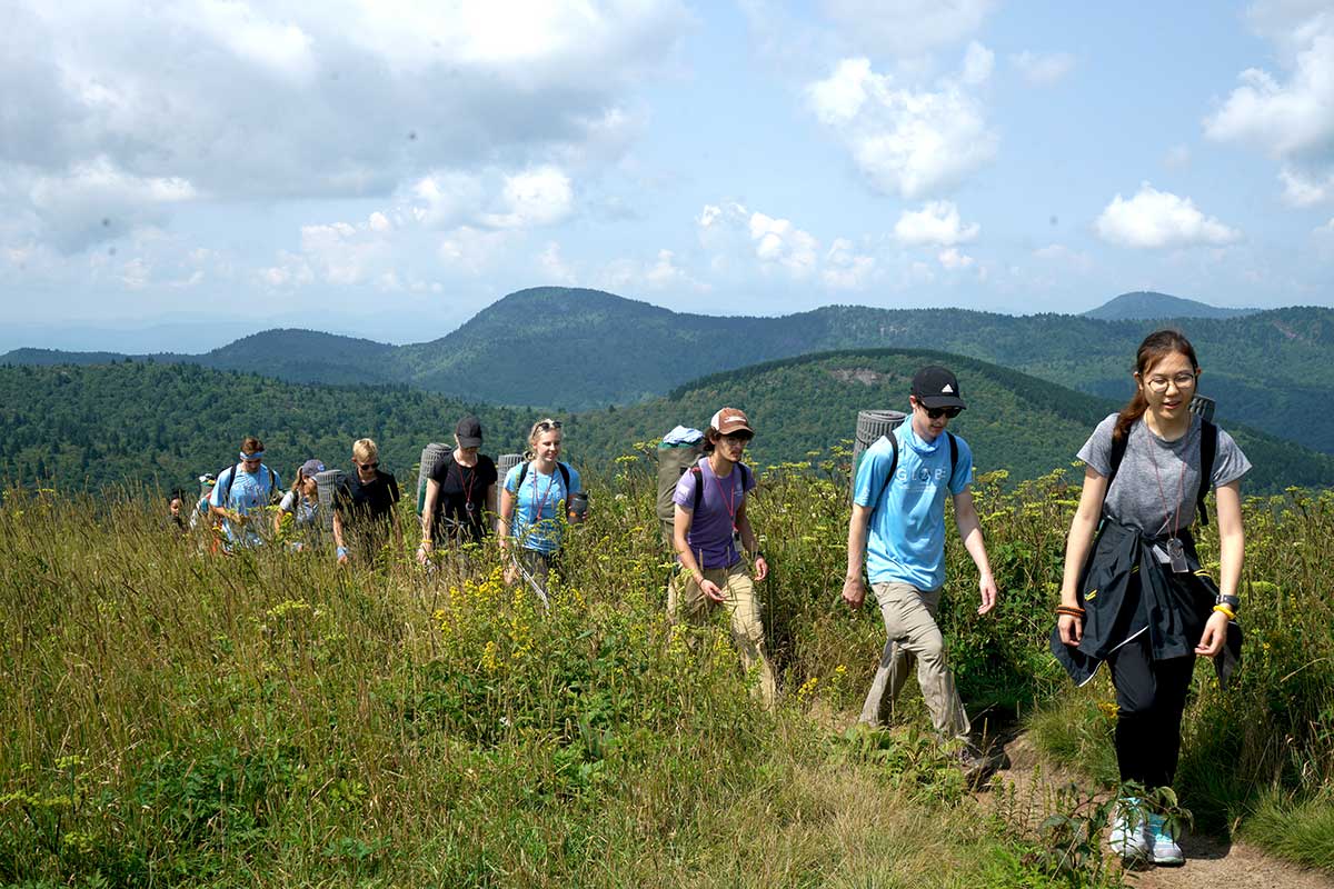 A line of university students hike across a ridge in the Blue Ridge Mountains of North Carolina.