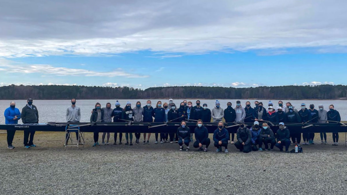 Women's rowing team poses beside new Vespoli racing shell 