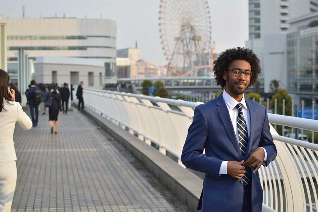 Phillips Ambassador T.J. Turner buttons his suit jacket on a bridge in Tokyo.