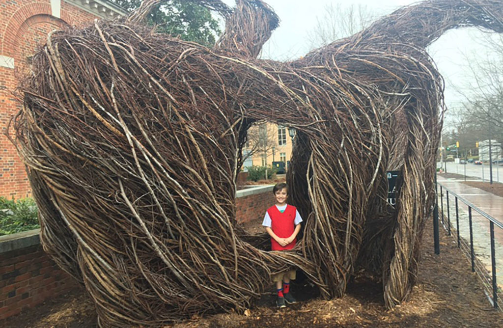 A member of the Hamel family stands inside a  sculpture outside of the Ackland Art Museum