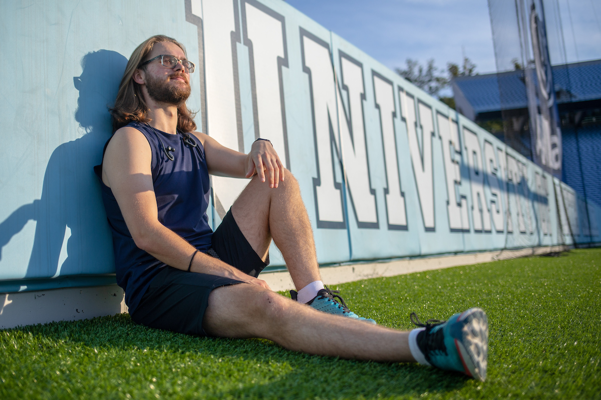 Carolina Covenant Scholar Matthew Wood leans on the wall on the football field.