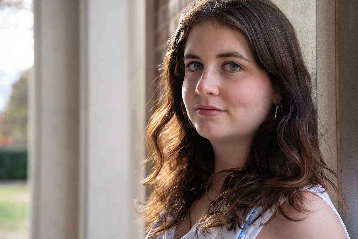 Mary leaning against a wall, smiling