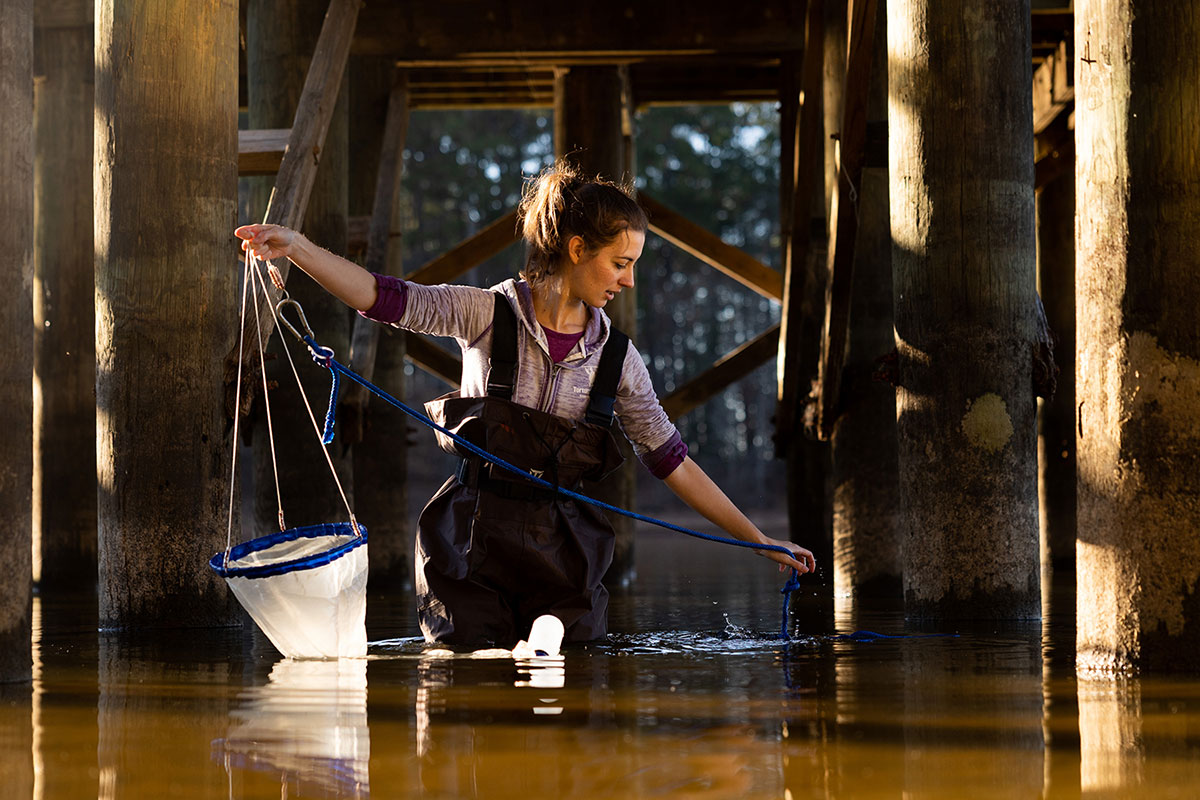 Emily holding a net while standing on a thigh deep water level lake