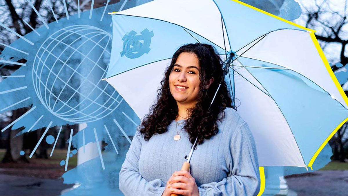 Dalal holding a UNC branded umbrella with blue and white shades