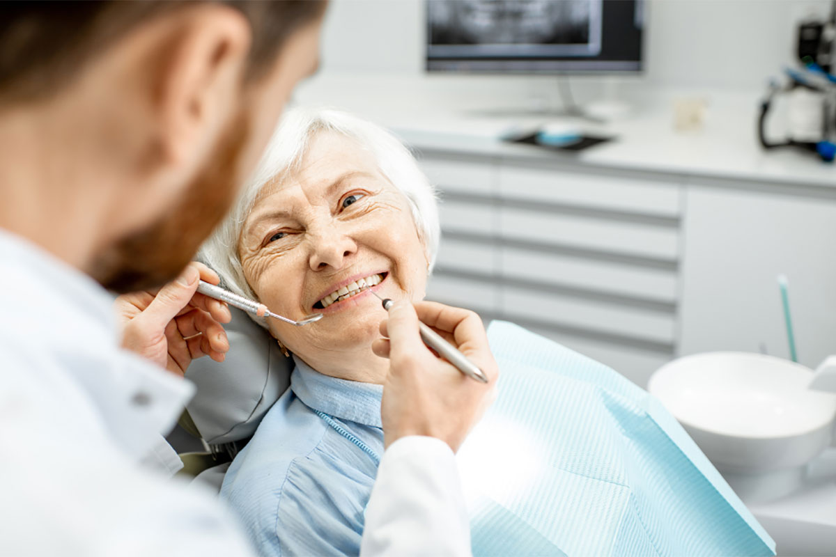 Dentist holding tools close to elderly female patient's teeth