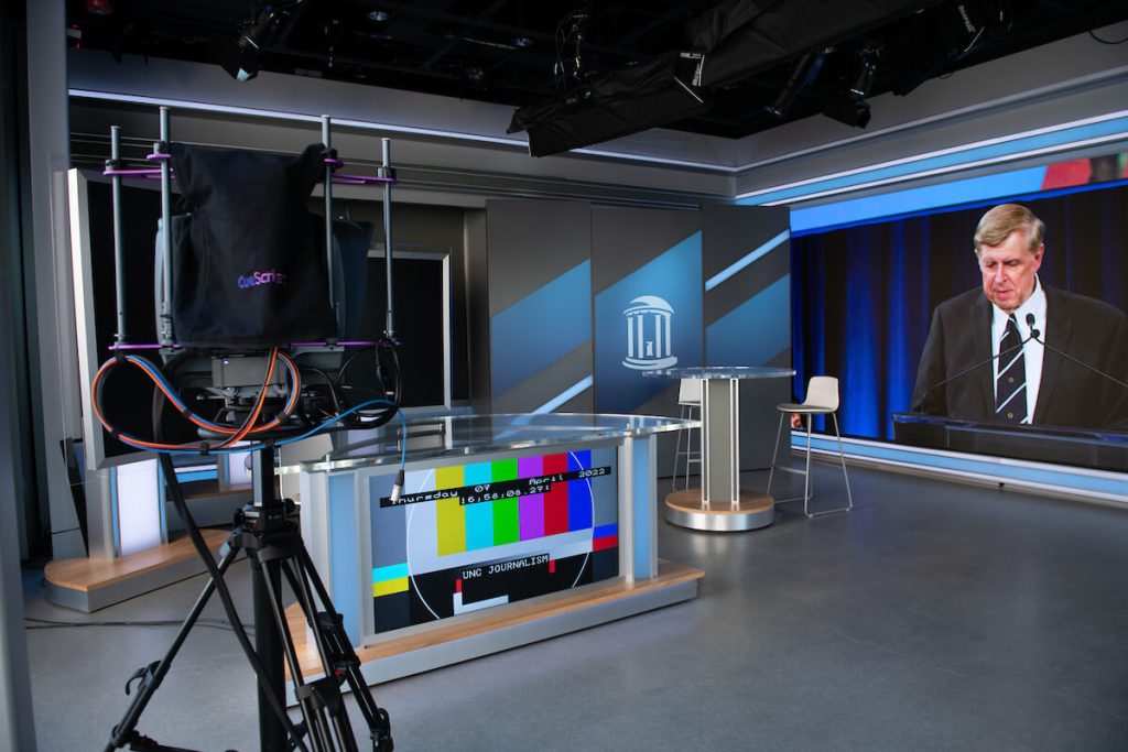 Broadcast studio inside the Curtis Media Center, with a desk and large screen to the side like in a professional news studio