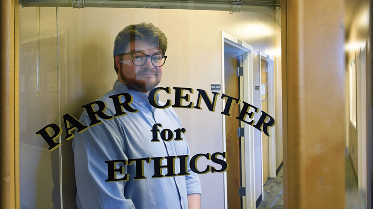 Alex Richardson stands behind a window that reads Parr Center for Ethics