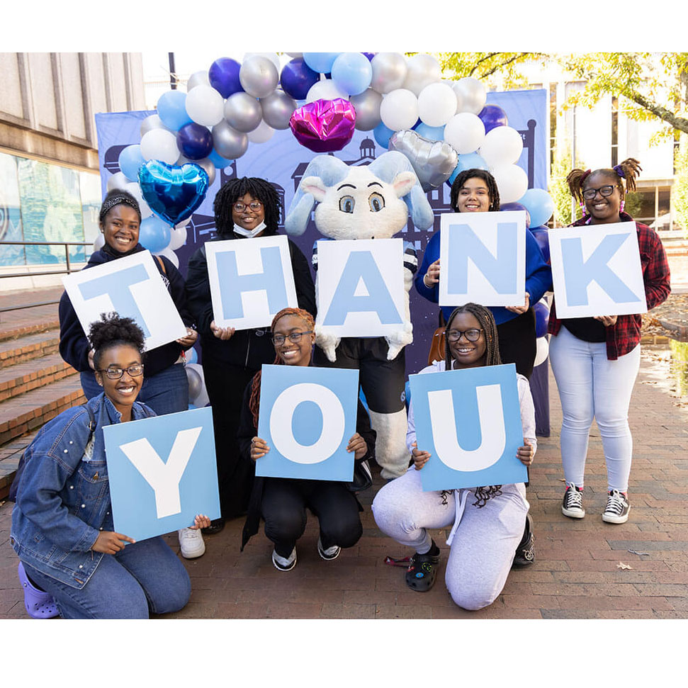 Carolina students and mascot hold up signs thanking donors to UNC-Chapel Hill