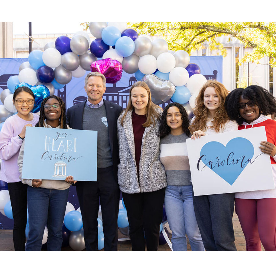 Carolina students and Chancellor Kevin Guskiewicz hold up signs thanking donors to UNC-Chapel Hill