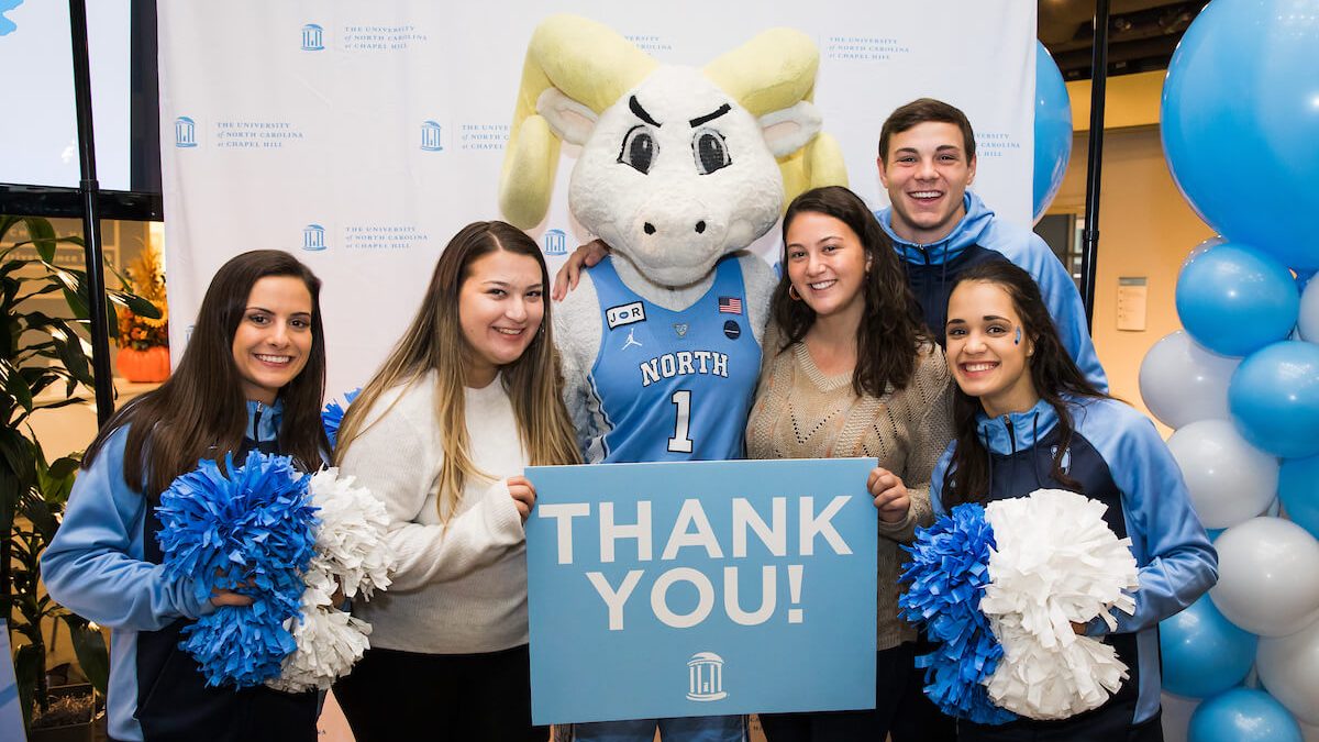 Carolina students, cheerleaders and mascot hold up a sign thanking donors to UNC-Chapel Hill