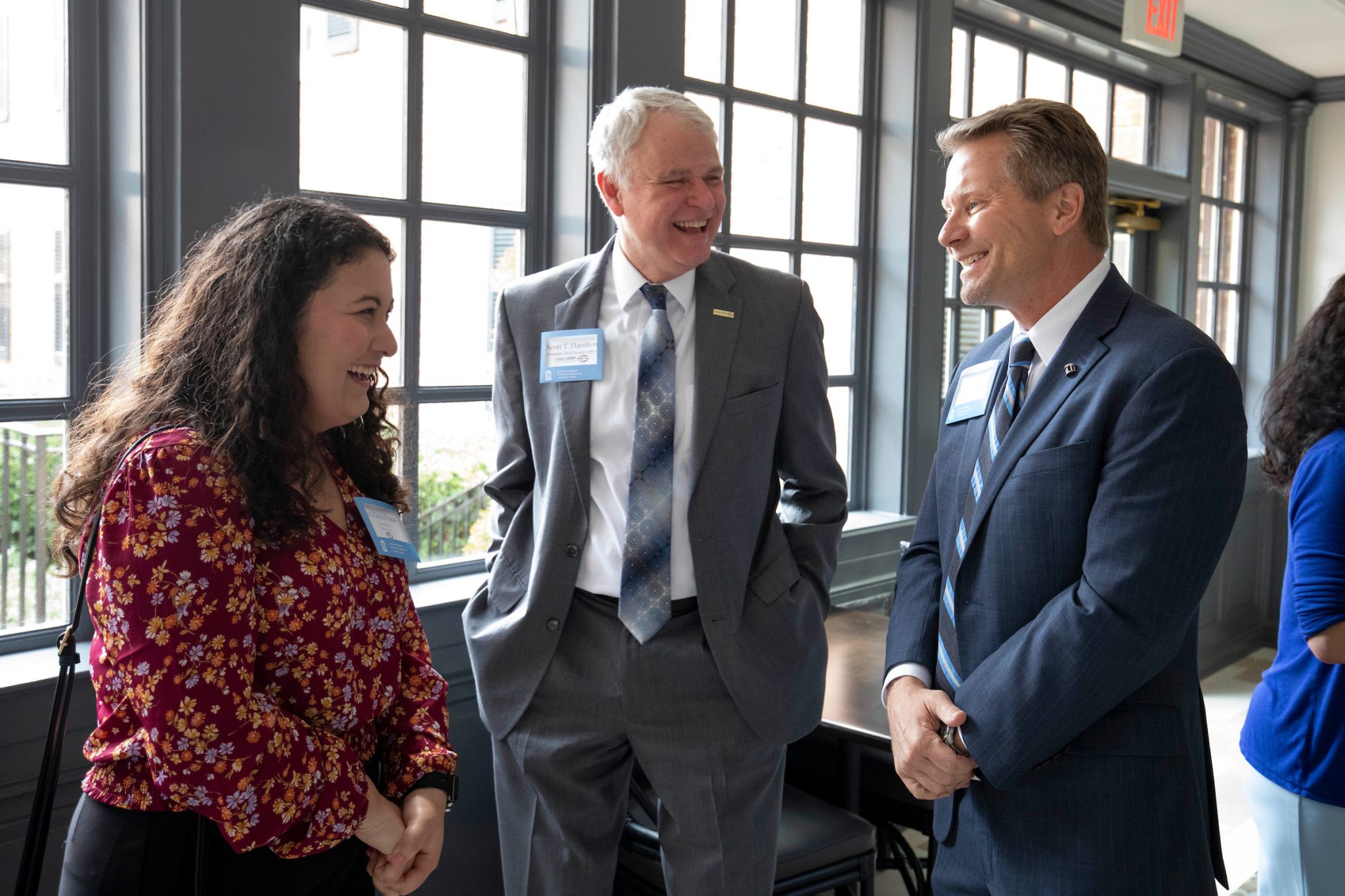 Ana Zurita Posas, Scott Hamilton, and Kevin Guskiewicz stand laughing at the Golden LEAF Luncheon
